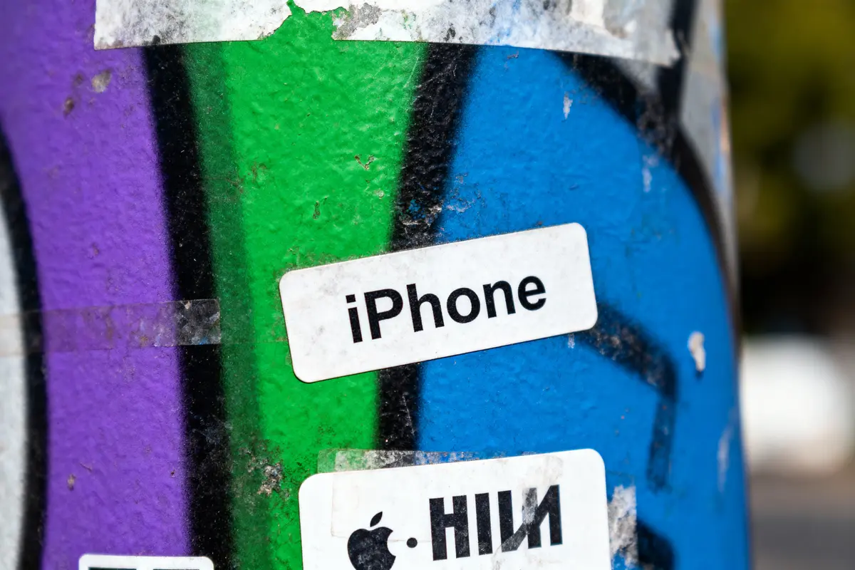 Autocollants "iPhone" sur fond de mur coloré vert, bleu et violet avec graphismes.