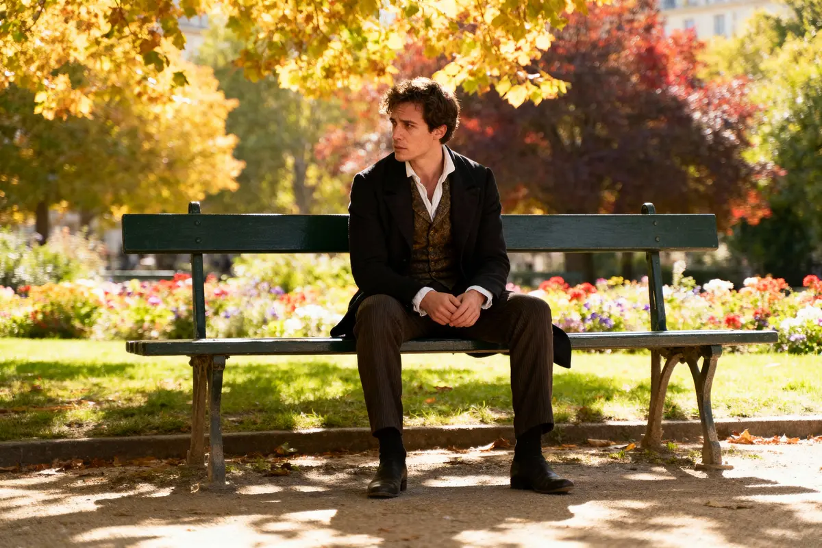 Homme assis sur un banc dans un parc automnal, entouré d'arbres aux feuilles colorées.