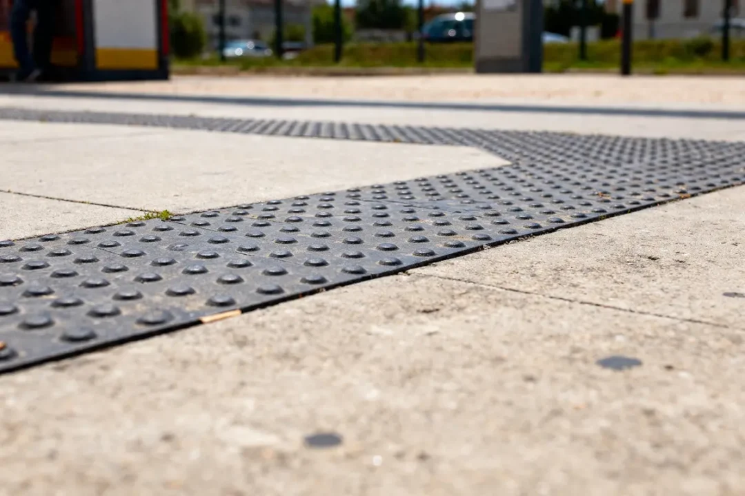 Surface de dalle béton avec bande de guidage podotactile en extérieur urbain