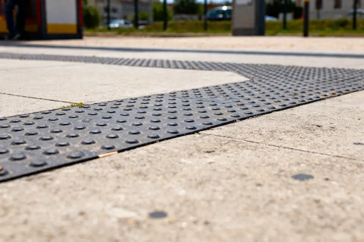 Surface de dalle béton avec bande de guidage podotactile en extérieur urbain