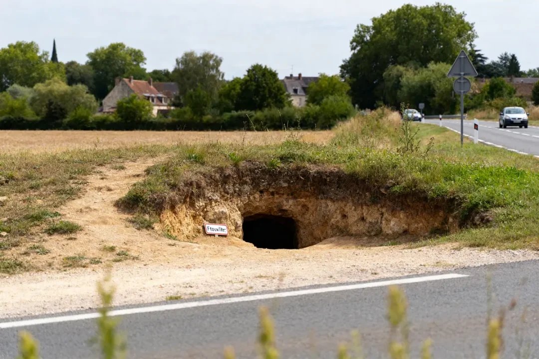 Terrerie près d'une route avec entrée indiquant fouilles archéologiques en campagne rurale.