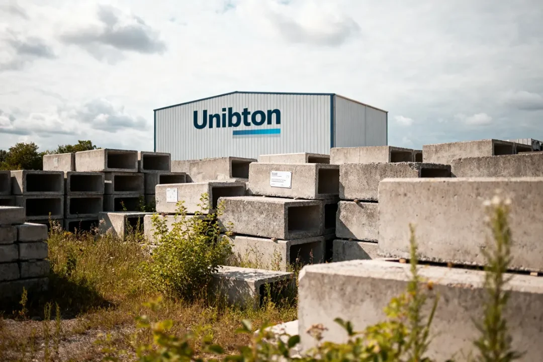 Dépôt de blocs de béton devant le bâtiment Unibeton avec ciel nuageux
