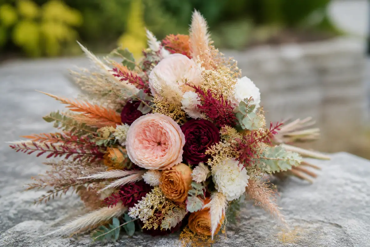 Bouquet de mariée champêtre avec fleurs séchées et feuillage sur fond naturel