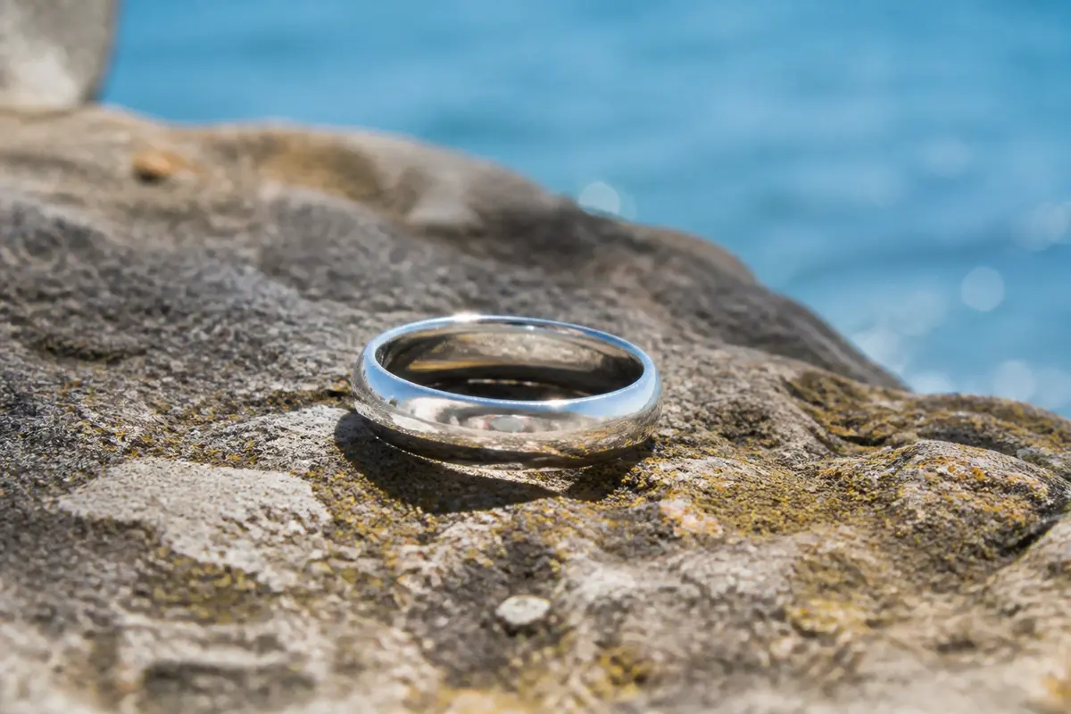 Anneau en argent masculin reposant sur un rocher face Ă la mer bleue