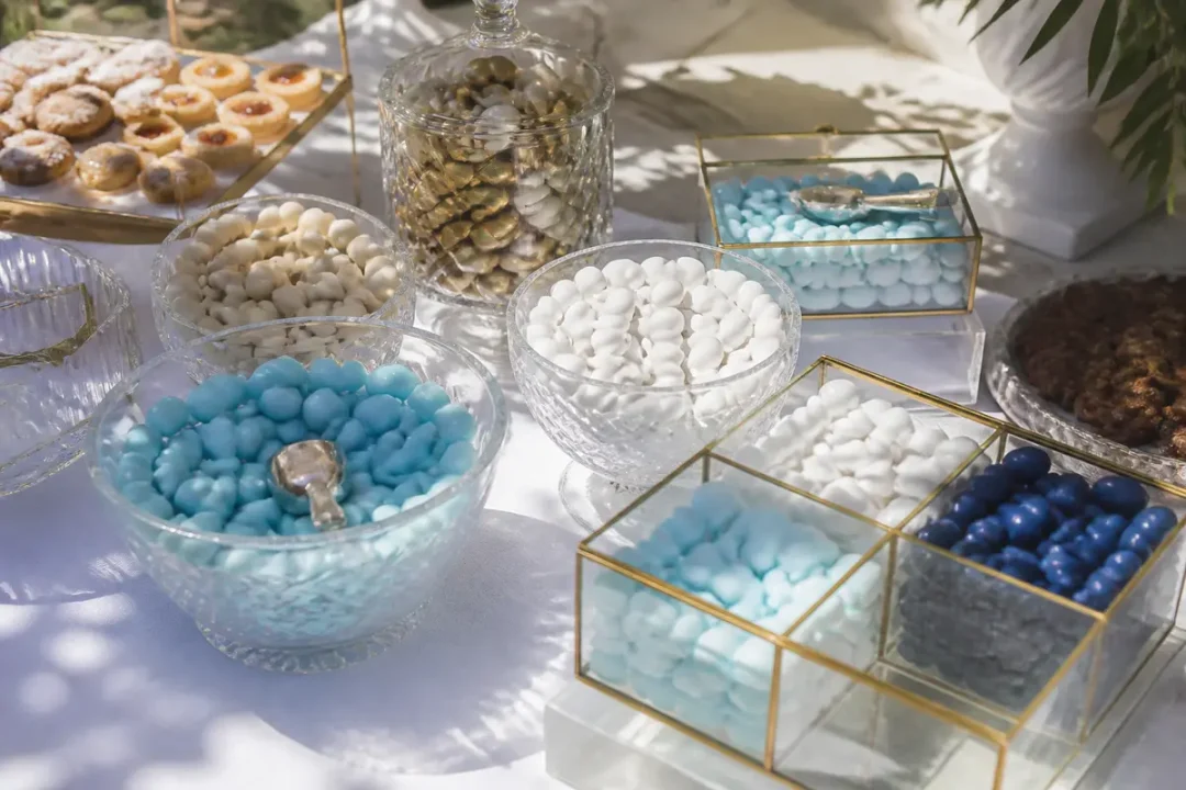 Assortiment de dragées cacher colorées présentées dans des bols en verre sur une table blanche